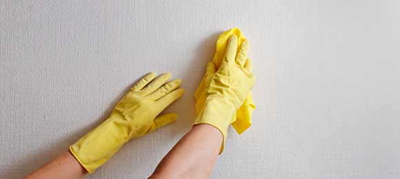 Mãos limpando uma parede com um pano