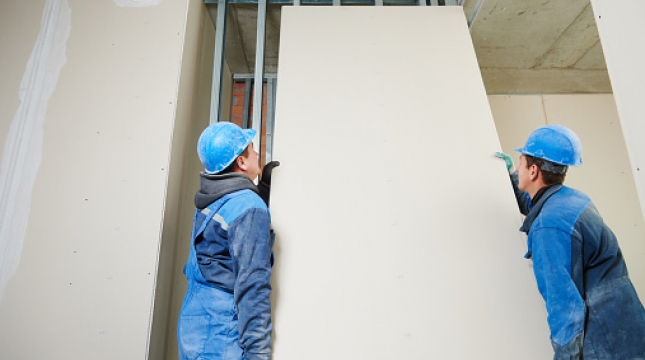 Dois homens instalando placas de drywall